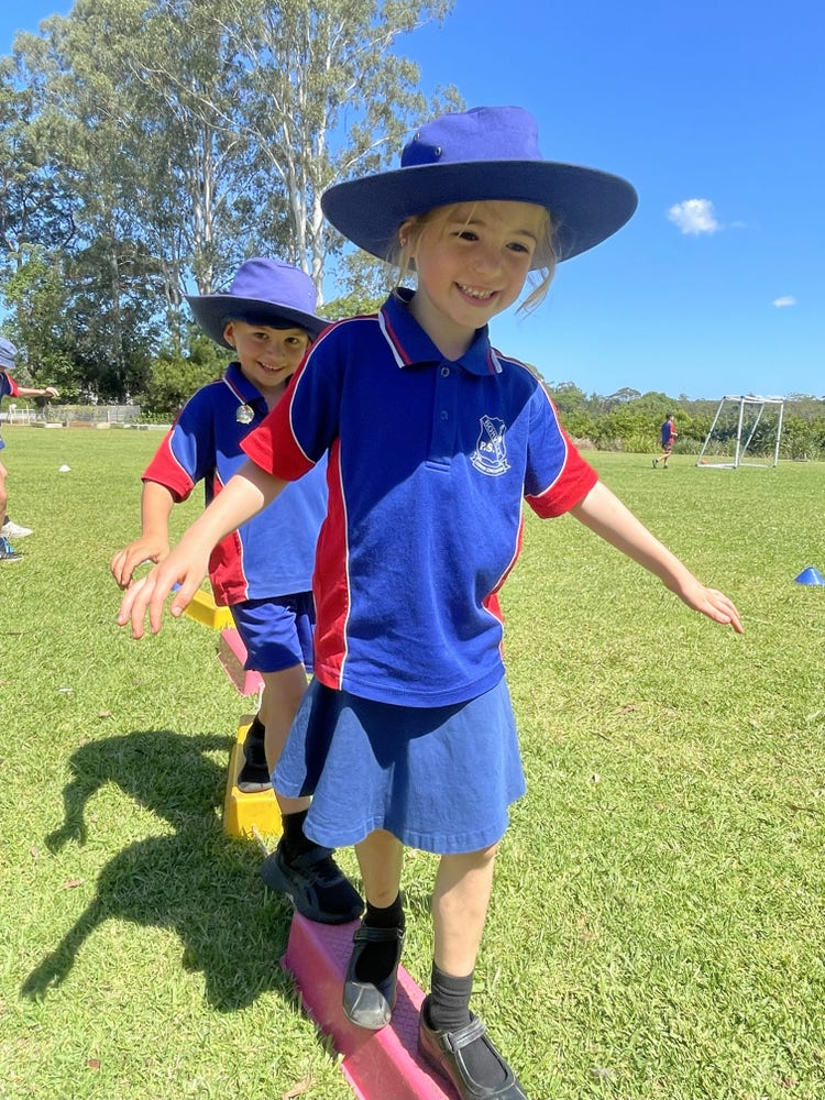 Two kindergarten students balancing on stepping blocks
