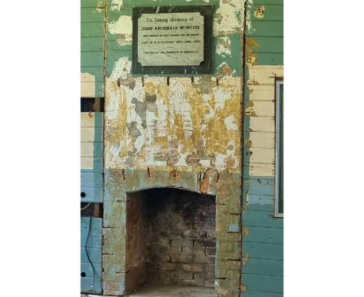 The original brick fireplace in one of the old classrooms, with a plaque above