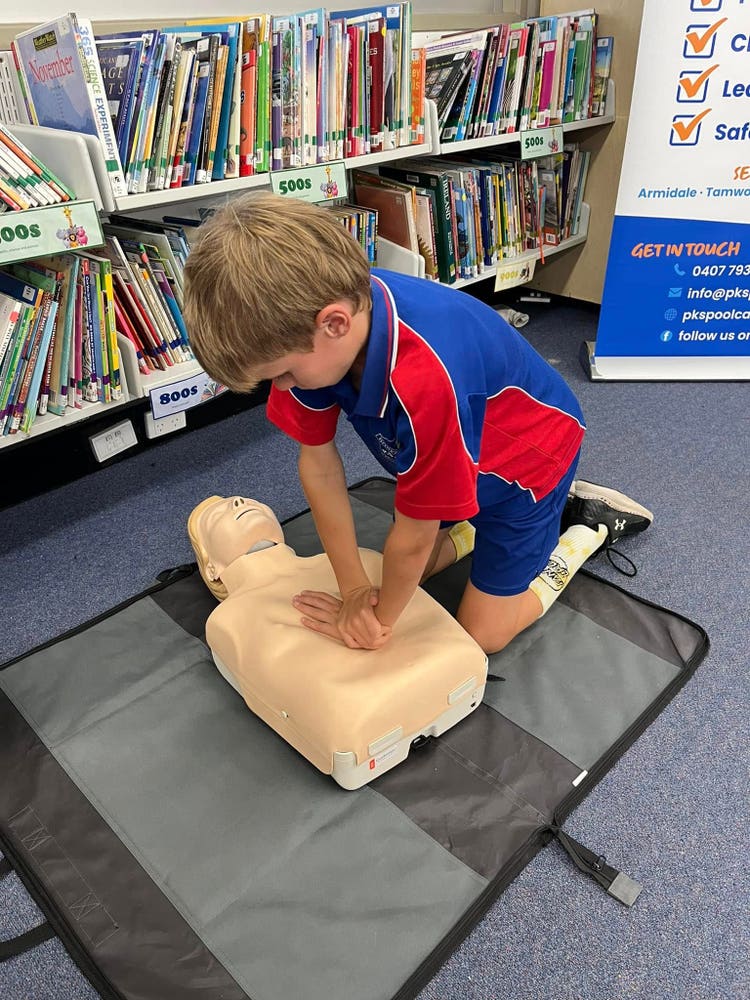 A year six student practising CPR on a dummy in the school library