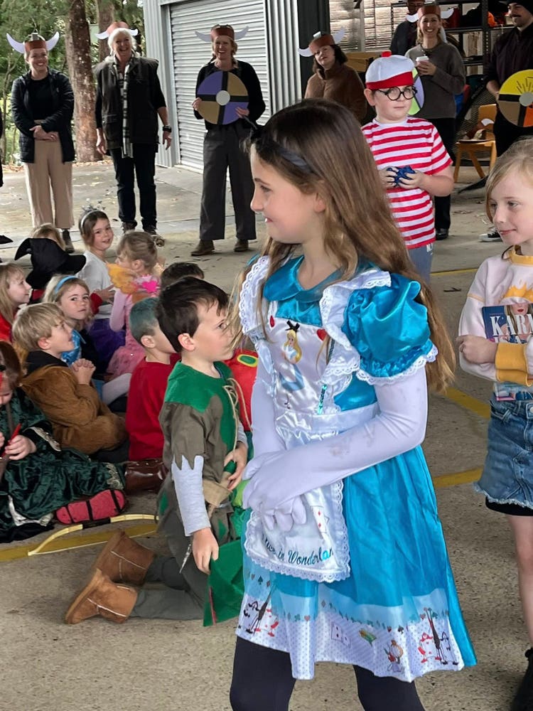 A girl in a Snow White costume during the book week parade, with other students in various costumes in the background.