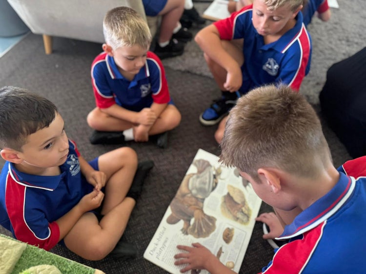 A year six student reading a story to two kindergarten students