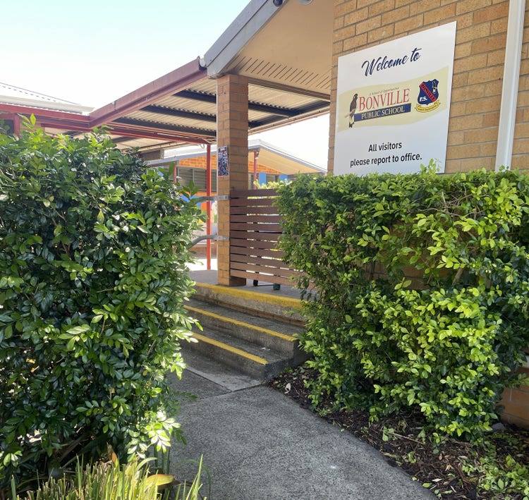 The pathway to the front office with green shrubs either side