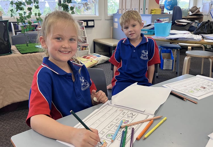 Two young students sitting at their desk with their writing in front of them